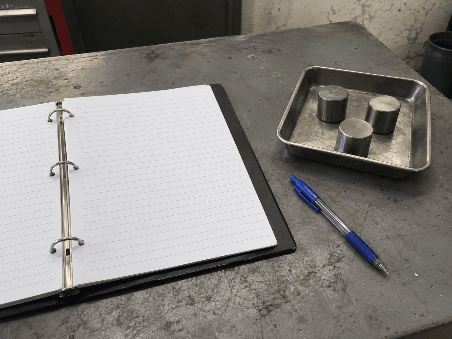 AI illustration of an open blank process binder, blue pen and three generic metal cylinders in a tray.