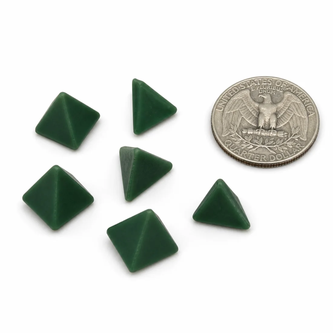 Six dark green pyramids and tetrahedrons arranged beside a US quarter
