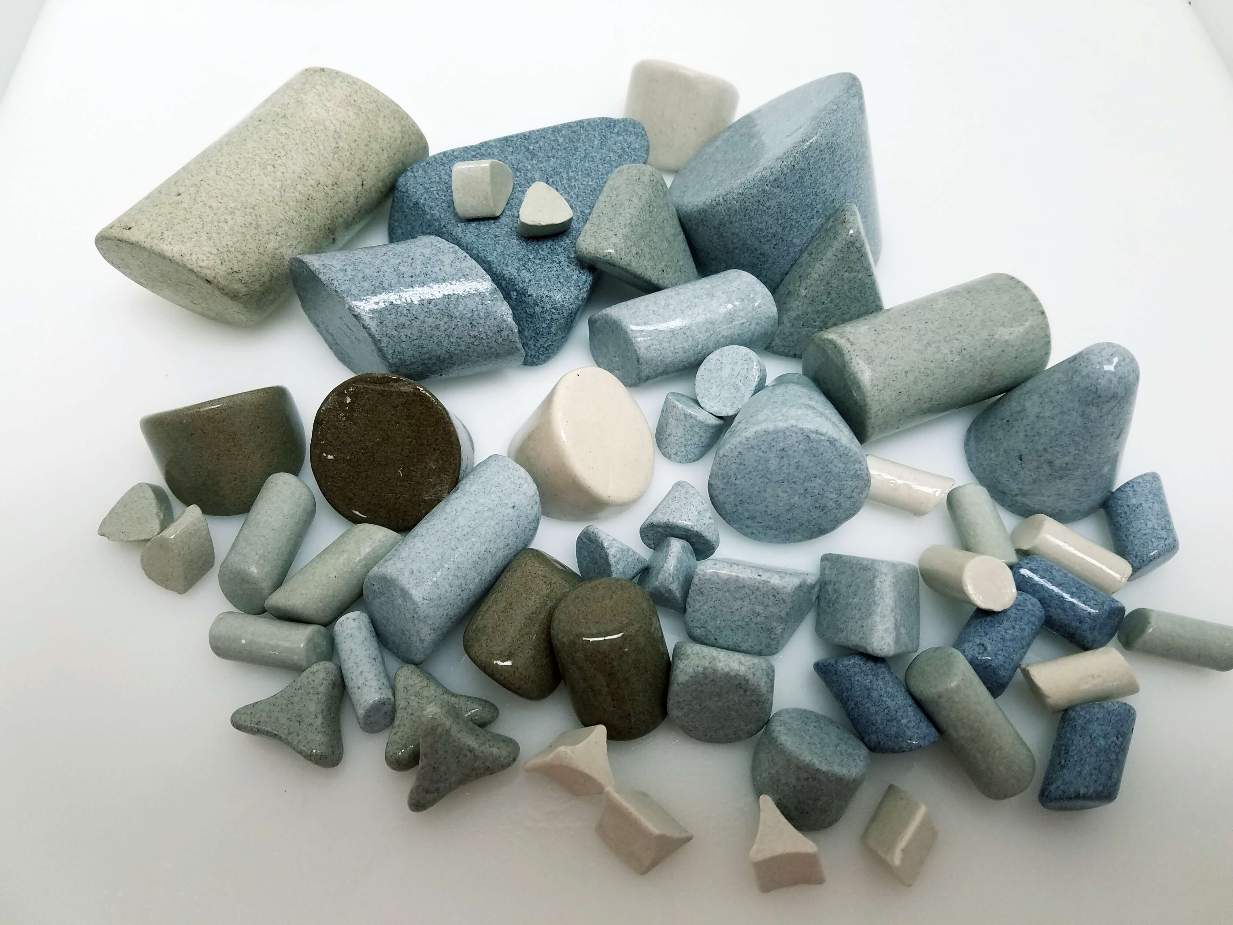 Actual ceramic finishing media from Vibra Finish, including angle-cut cylinders, triangles, cones, and tristars